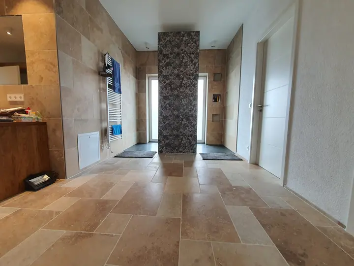 Mosaik und Naturstein: Flur mit Travertin-Boden und Säule aus Natursteinmosaik