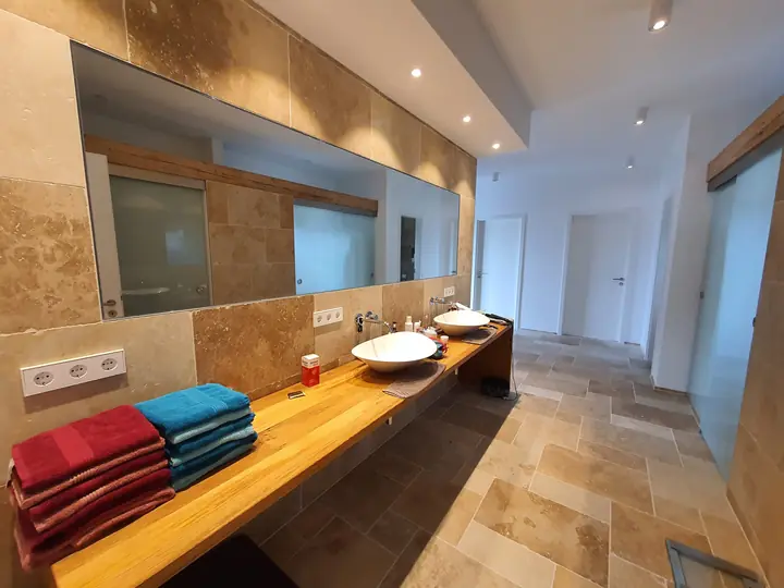 Bad mit Travertin-Wand und Waschtisch aus Holz