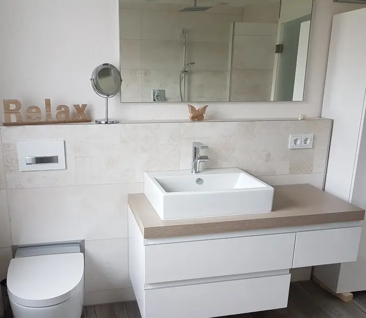 Helles Bad mit gefliester Vormauerung und Ablage, Aufsatzwaschbecken, Wand-WC und Boden in Holzoptik